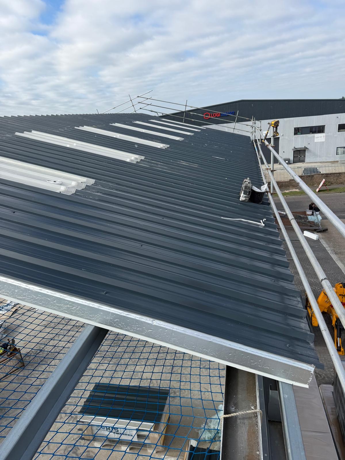 Industrial roof refurbishment with new sheets, rooflights and scaffold at the eaves