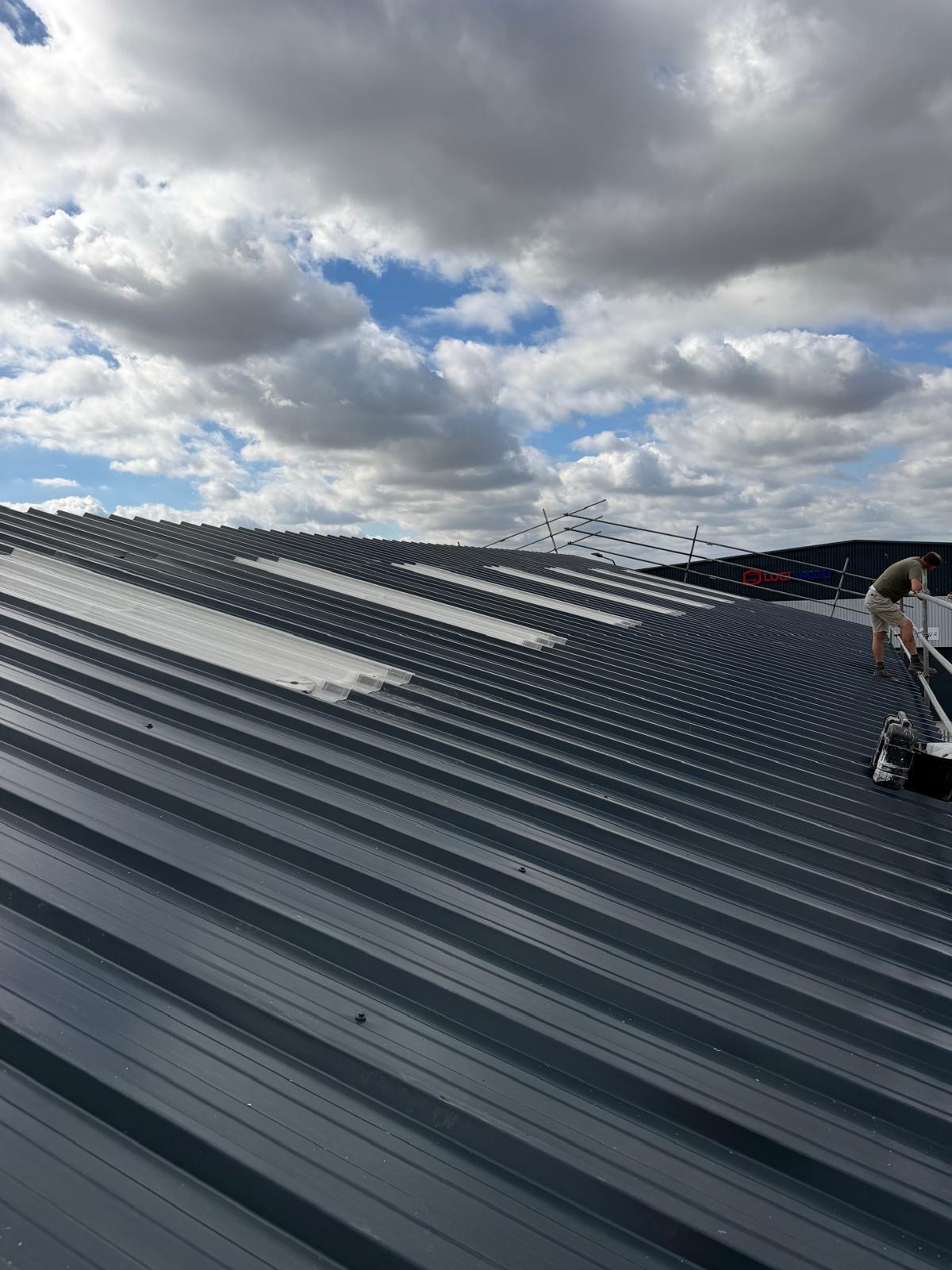 Industrial roof with new grey profiled sheets and rooflight strips being installed