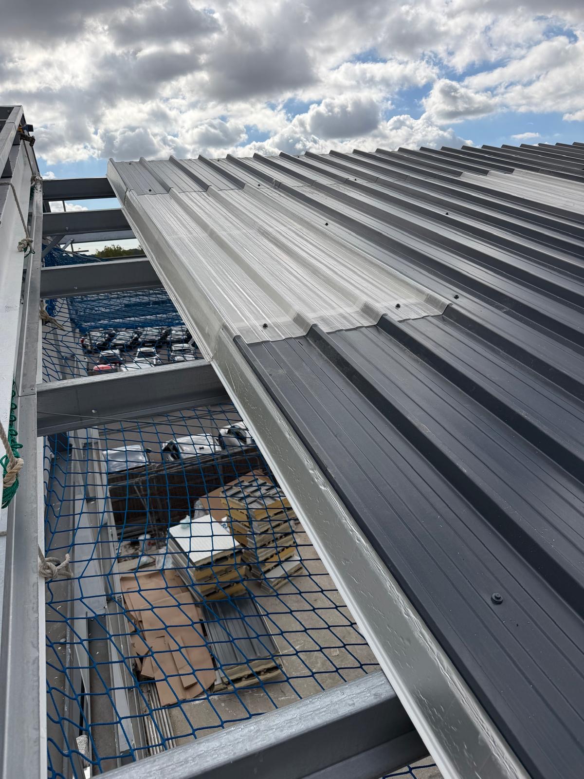 Translucent rooflight panel being fitted between new grey roof sheets