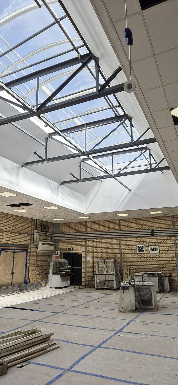 Interior refurbishment with exposed steel rooflight framing and protected floor