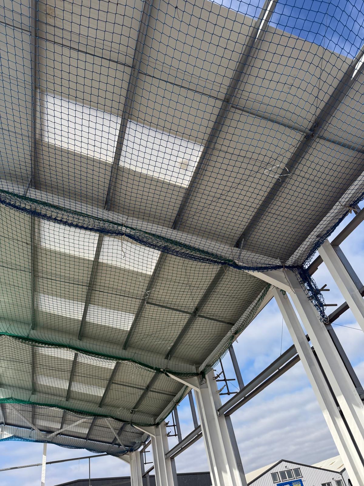 Interior liner panels installed under an industrial roof with safety netting below