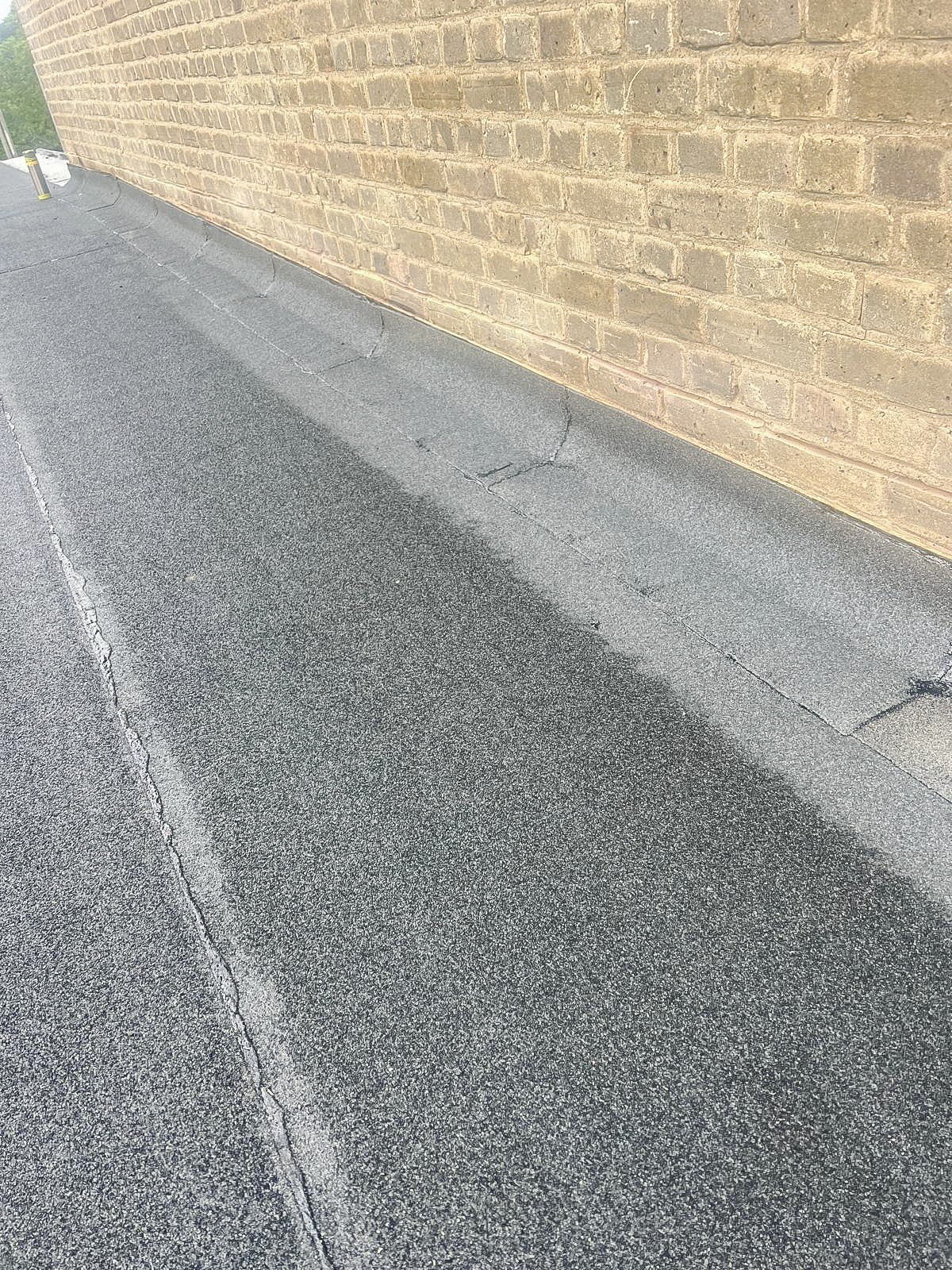 New flat-roof membrane finished against an existing brick wall