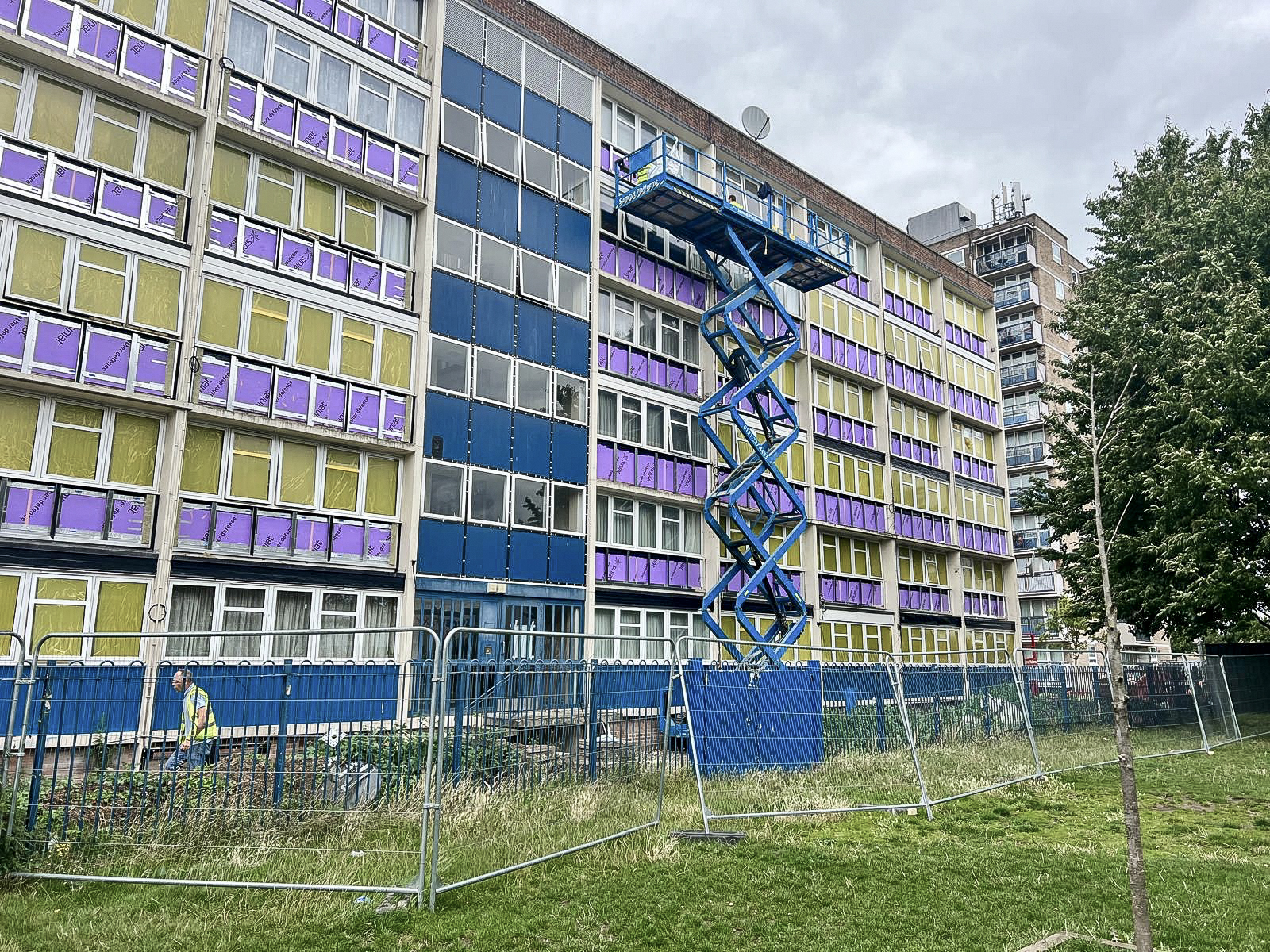 Wide view of a multi-storey facade refurbishment with access equipment on site